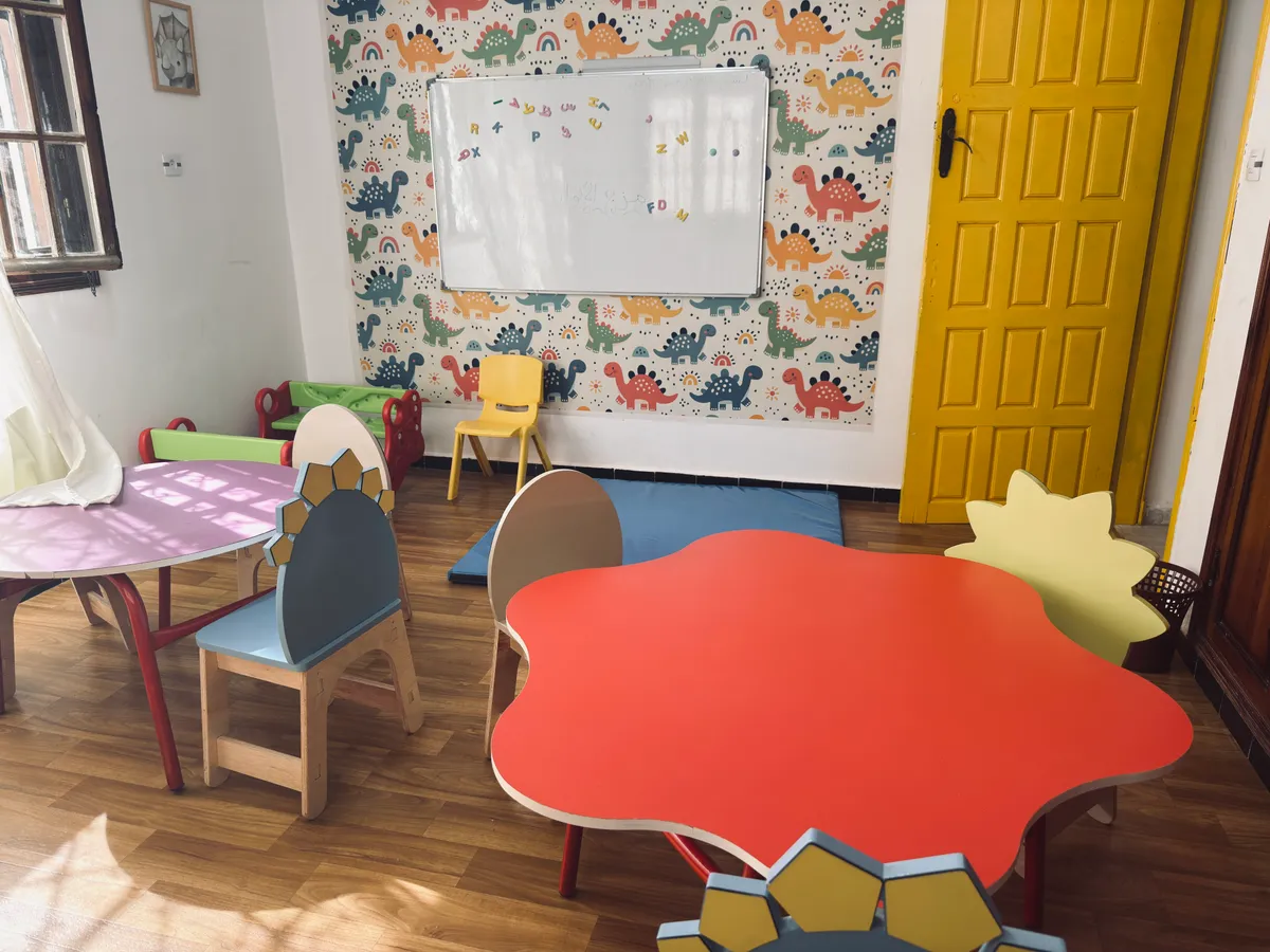 Flower-shaped table, a whiteboard and dinosaur-patterned wallpaper.