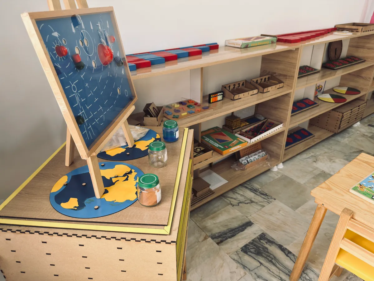 Montessori materials on low shelves: red and blue rods, continent puzzles and a solar system board.