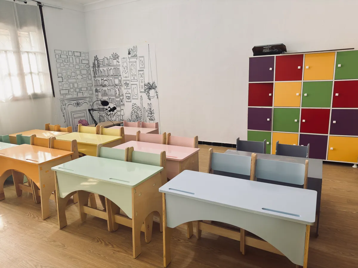 Classroom with pastel desks, colourful storage lockers and an illustrated wall.