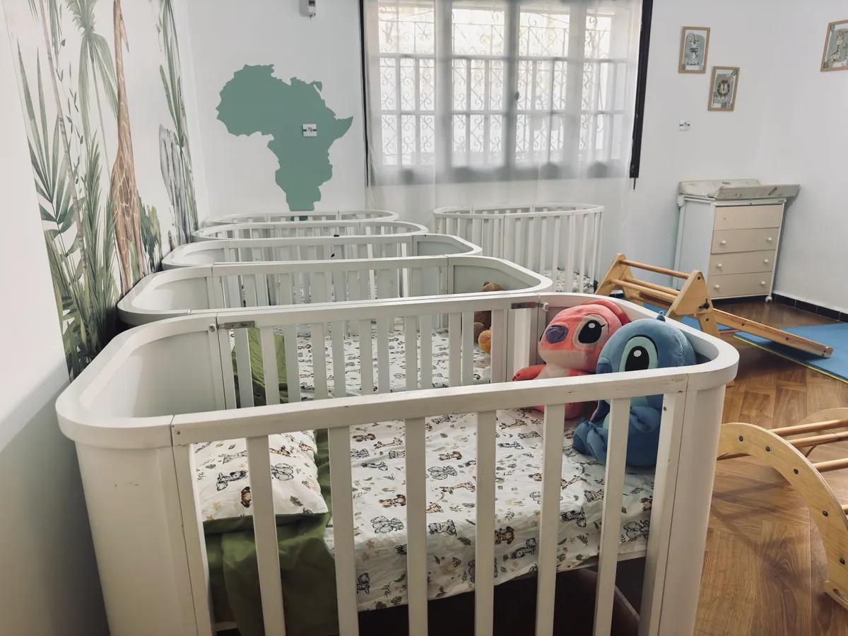 Quiet room with white cots, soft toys and a map of Africa on the wall.