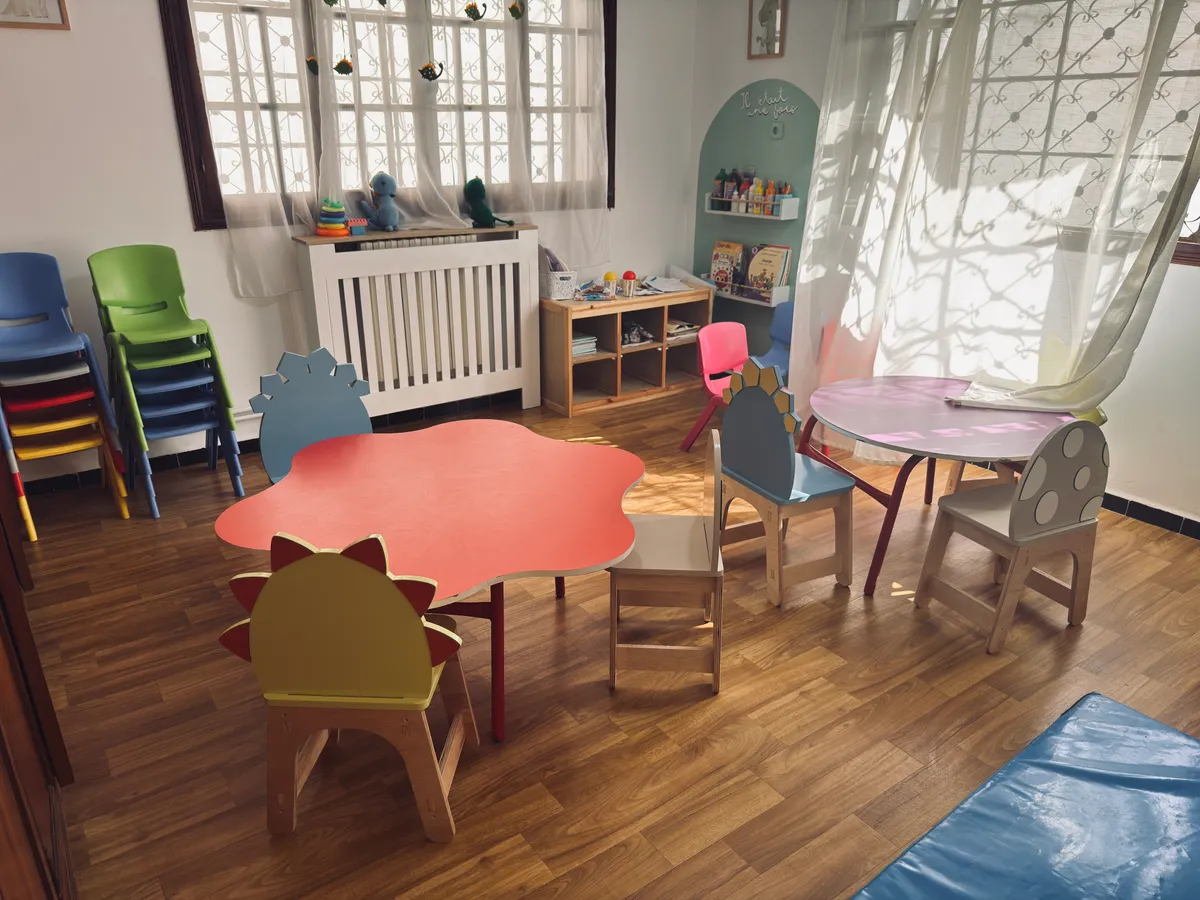 Activity room with a red flower-shaped table, colourful chairs and a reading nook.