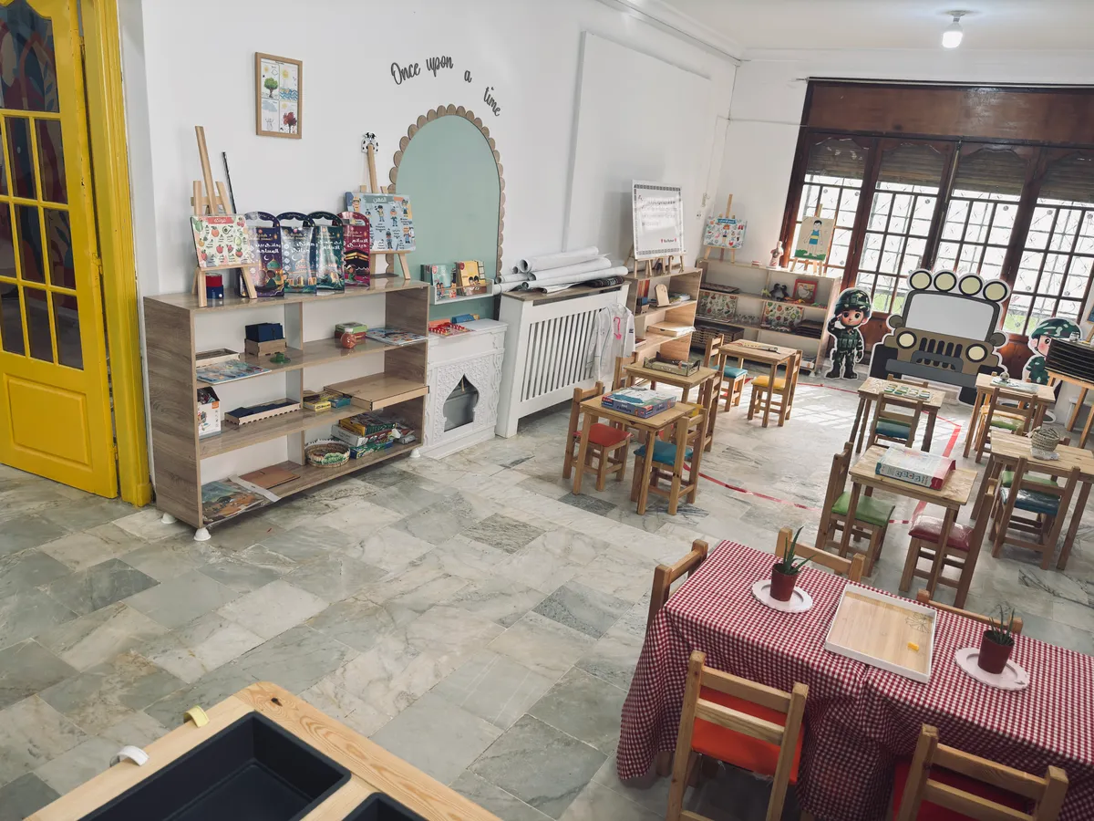 Room with yellow doors: toy shelves, an arched reading nook and tables for children.