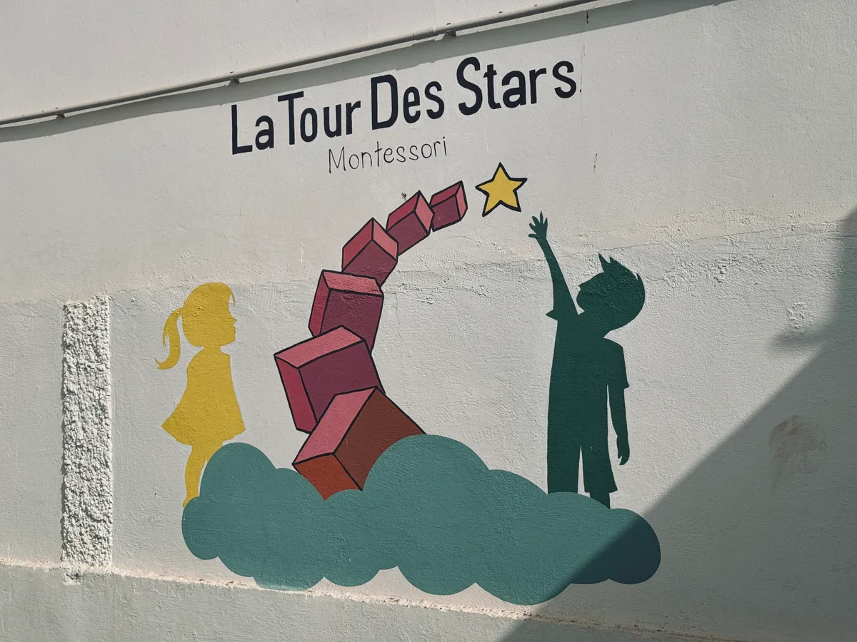 Mural reading “La Tour des Stars Montessori”: two child silhouettes, a tower of pink cubes and a star.