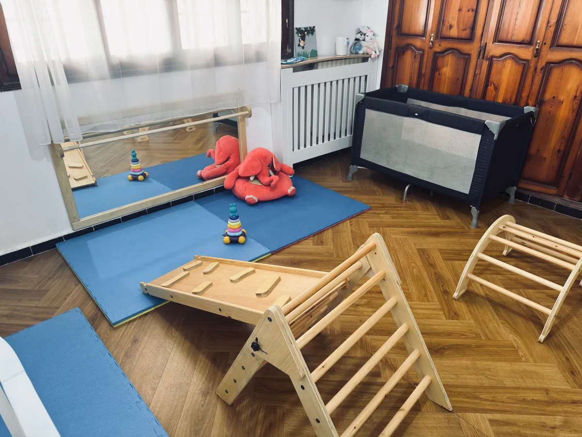 Little ones’ area: a wooden climbing triangle with a ramp, a low mirror and floor mats.
