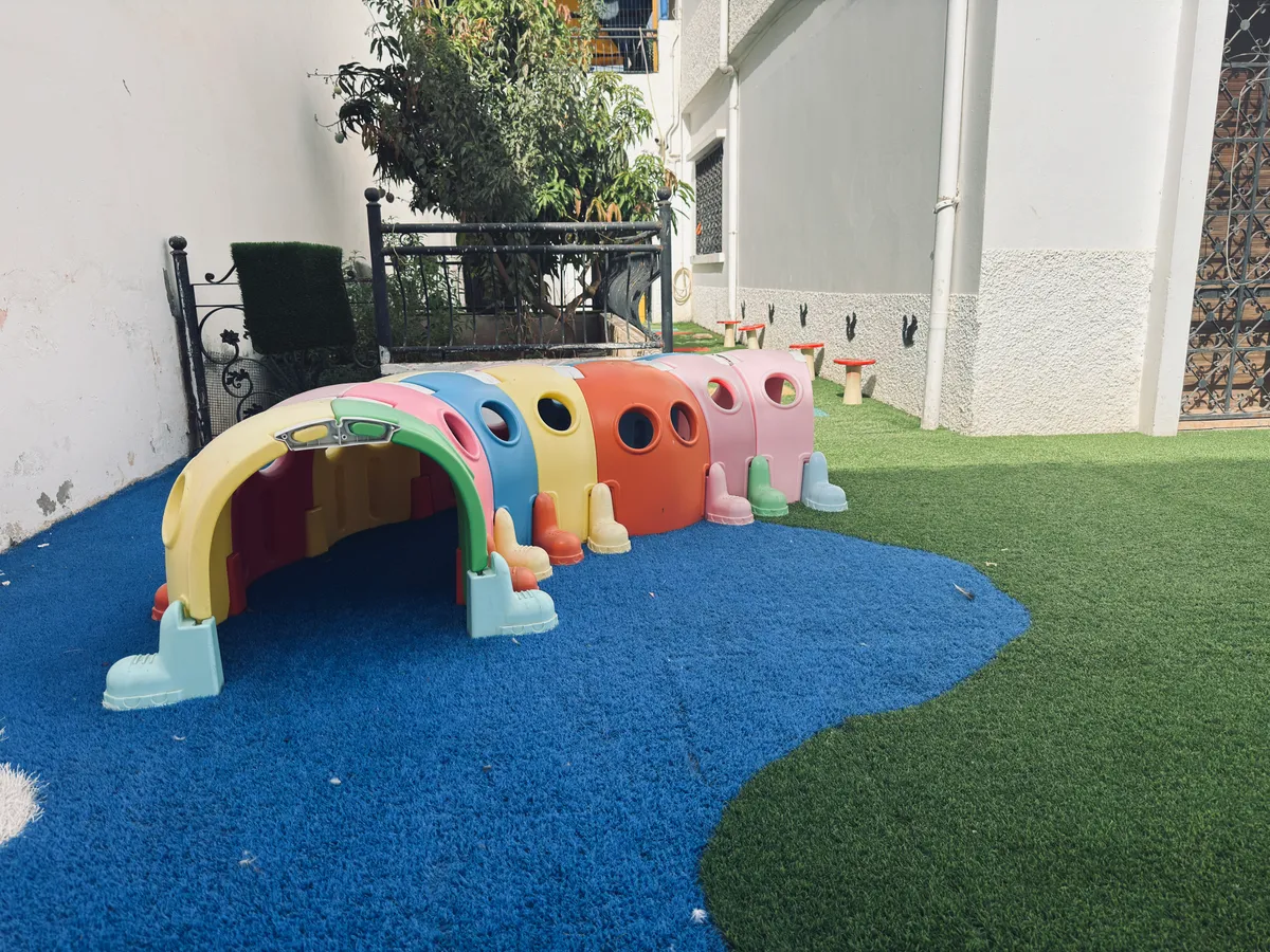 Pastel caterpillar tunnel on a blue surface in the garden.