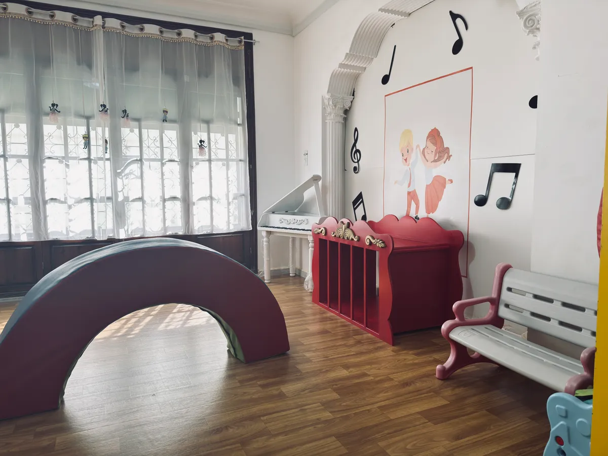 Large rocking arch, a white bench and musical decor in a sunlit room.