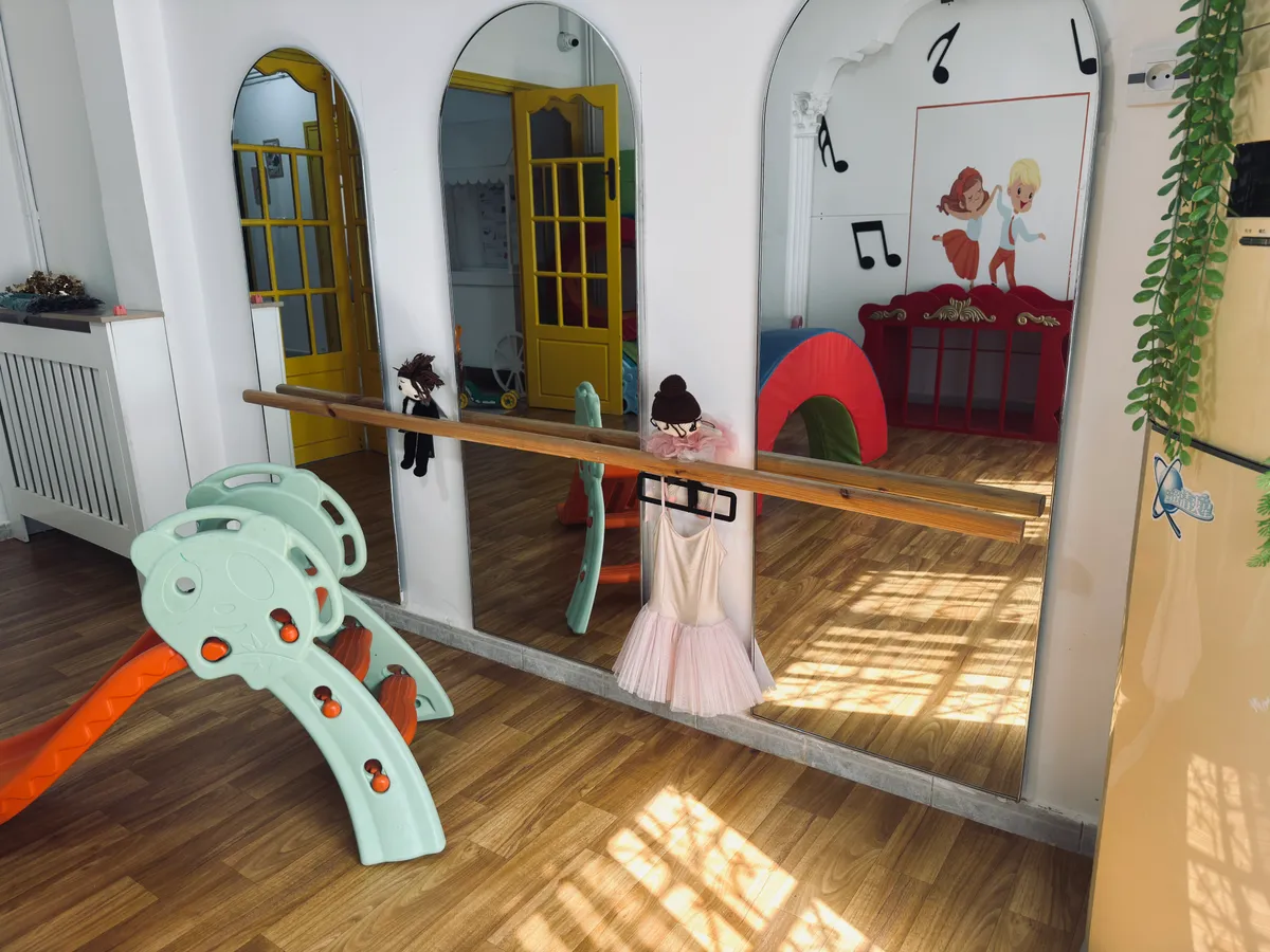 Wall of arched mirrors with a wooden handrail, a slide and mats.
